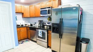 Una cocina con armarios de madera, un refrigerador de acero inoxidable, un microondas y un horno.
