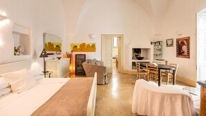 A spacious room with a bed, a dining table, and a kitchen area.