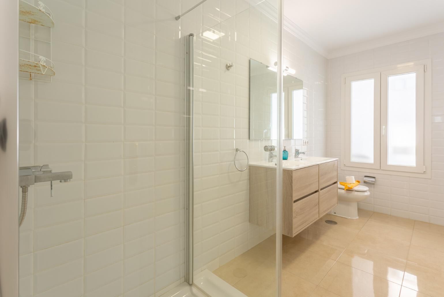 Un baño moderno con ducha de vidrio, tocador con espejo y un inodoro.