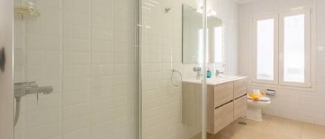 A modern bathroom with a glass-enclosed shower, a vanity with a mirror, and a toilet.