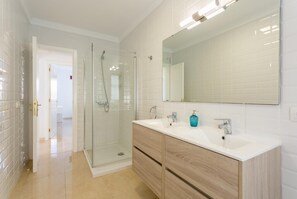 Ein modernes Badezimmer mit einer Duschkabine aus Glas, einem Doppelwaschtisch und einem großen Spiegel.