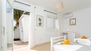 A bright bedroom with two beds, a window, and a door leading to a balcony. - Villa Diego - Five Bedroom Villa, Sleeps 10 (Puerto del Carmen)