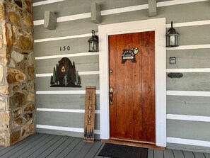 A wooden door with a 'Welcome' sign, a 'No Smoking' sign, and a '130' number above it.
