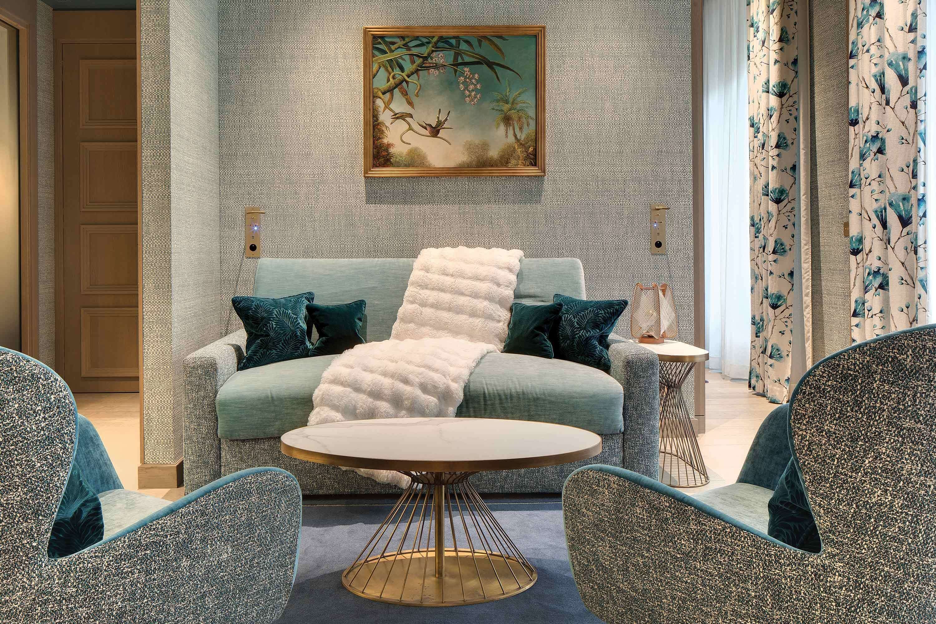 Una habitación con un sofá, una mesita redonda y dos sillones.