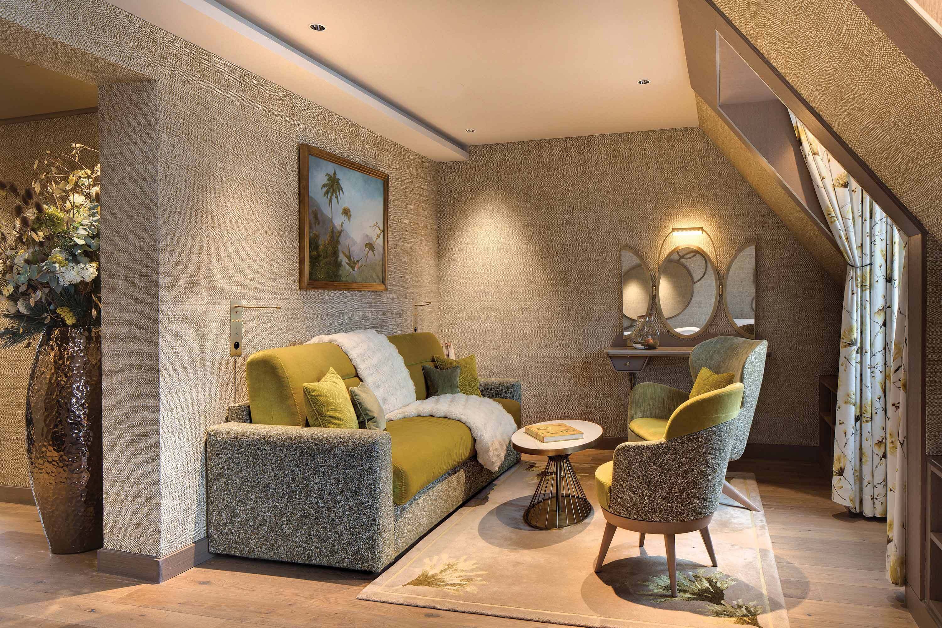 A modern living room with a sofa, armchairs, a coffee table, a painting, and a large vase.