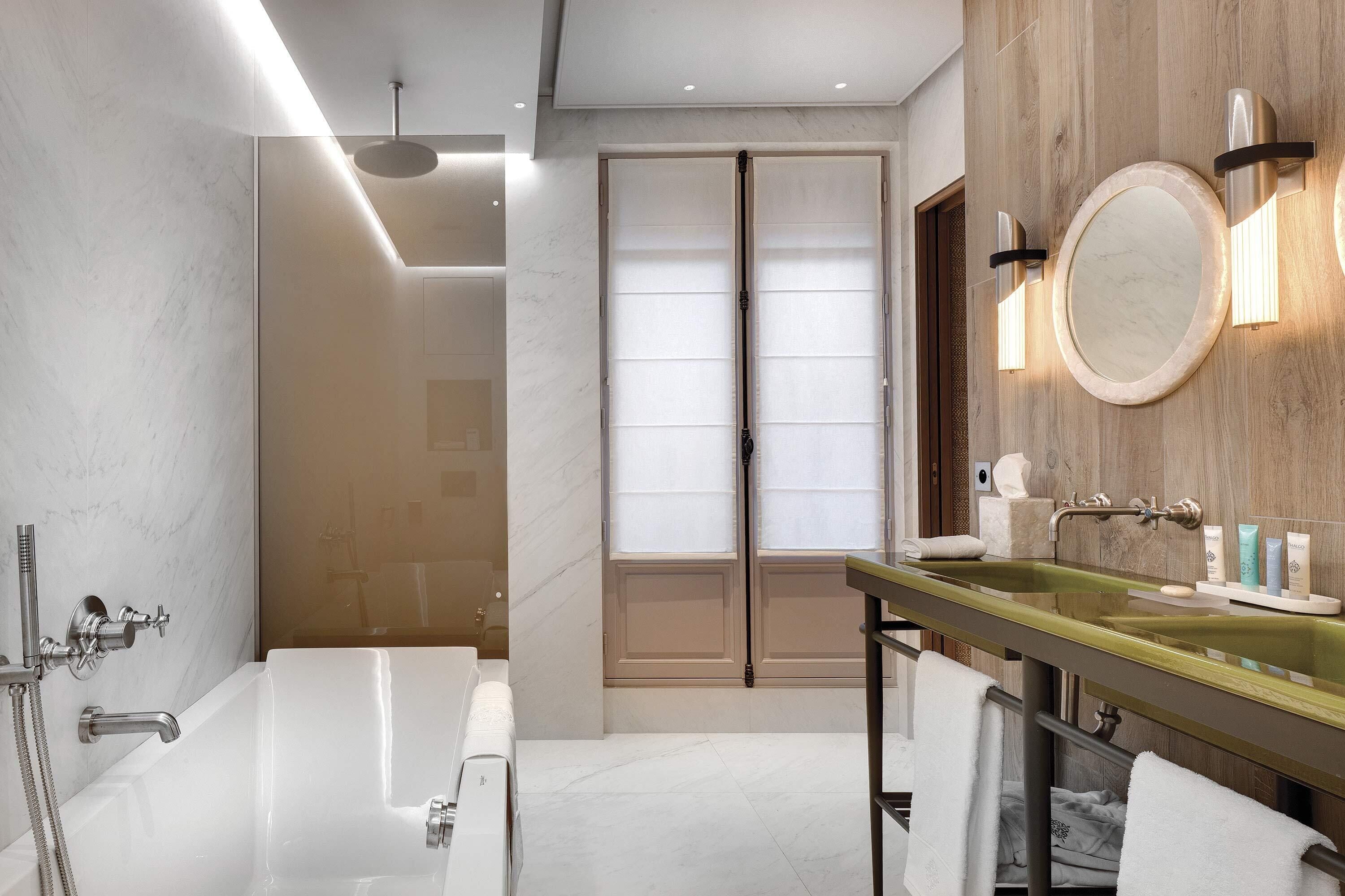 A modern bathroom with a large bathtub, a glass-enclosed shower, and a vanity with a mirror and lighting.
