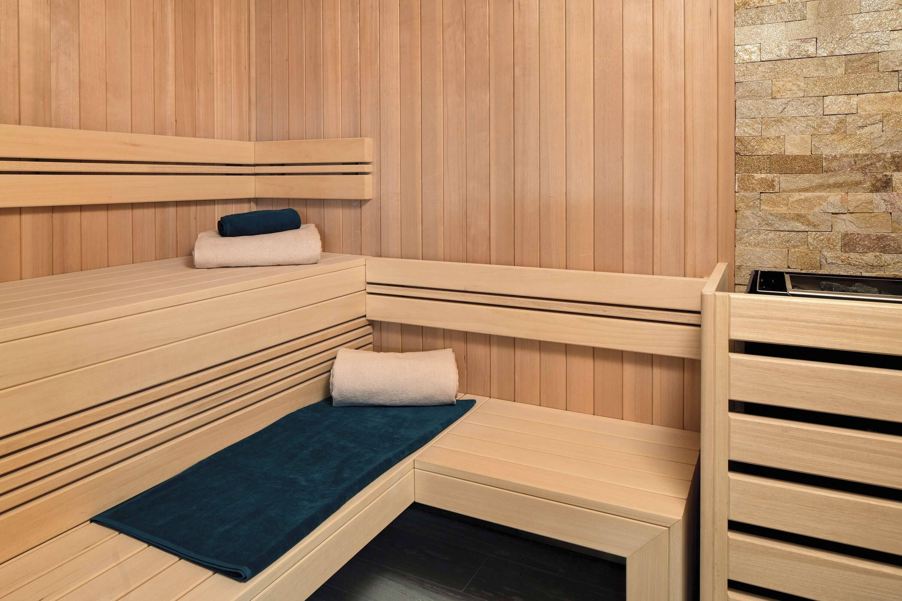 A sauna with wooden benches and a stone wall.