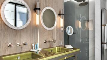 Un baño con un espejo grande, un lavamanos y una ducha.