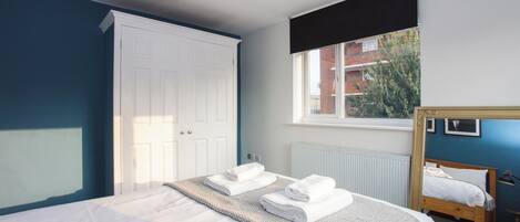 A bedroom with a bed, a window with a view, a wardrobe, and a mirror.