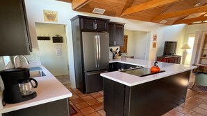 A modern kitchen with a central island, stainless steel appliances, and a coffee maker. - Uptown Boho Comfort - Uptown Sedona - Beautiful 3 Bedroom Home w/a View (Sedona)