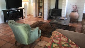 A living room with a television, a fireplace, a sofa, and a patterned rug. - Uptown Boho Comfort - Uptown Sedona - Beautiful 3 Bedroom Home w/a View (Sedona)