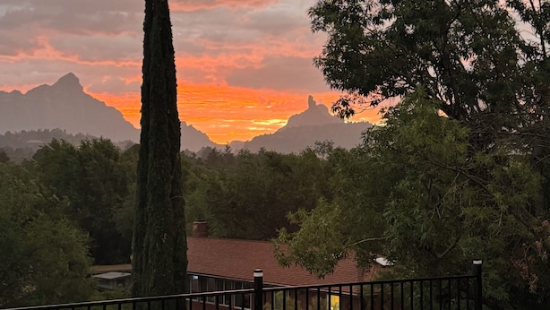A sunset view with a tall tree, a fence, and a house in the foreground. - Uptown Boho Comfort - Uptown Sedona - Beautiful 3 Bedroom Home w/a View (Sedona)