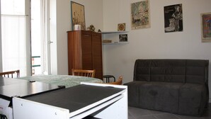 A room with a dining table, a sofa, a cabinet, and artwork on the walls. - Appartement champêtre - Déconnexion assurée (Poitiers)