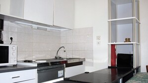 A compact kitchen with white cabinets, a black countertop, and a built-in oven. - Appartement champêtre - Déconnexion assurée (Poitiers)