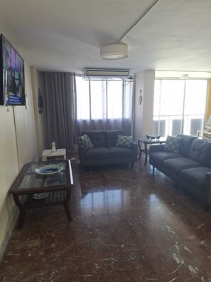 A living room with a sofa, a coffee table, and a TV.
