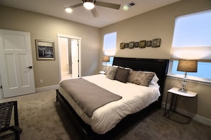 Une chambre à coucher comprenant un lit, une table de chevet, une lampe, une porte et un mur décoré de différents objets.