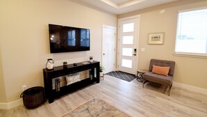 Un salon avec un téléviseur à écran plat, une console en bois foncé, un banc et un tapis.