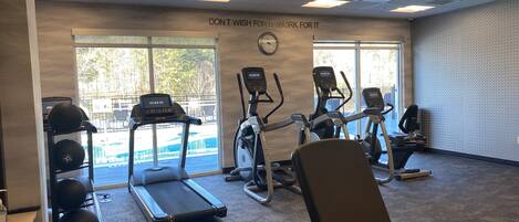 Un gimnasio con cintas de correr, elípticas y equipo de levantamiento de pesas.
