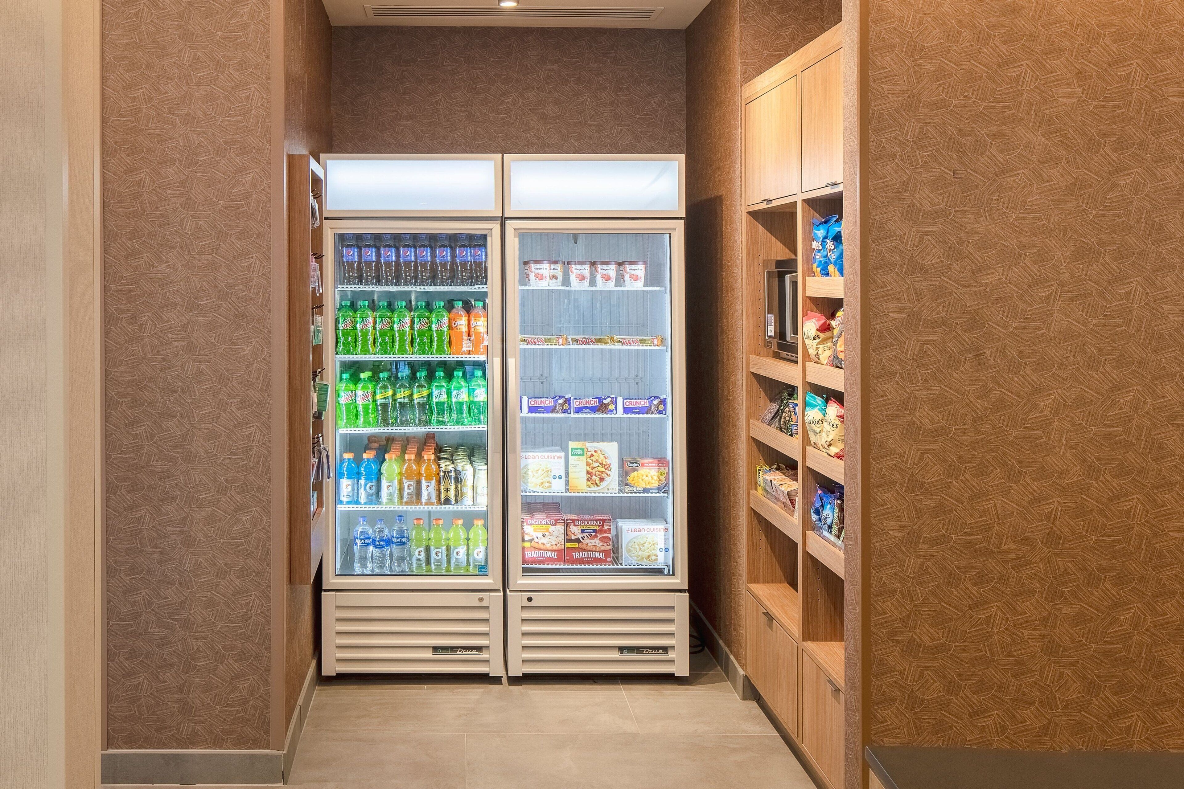 A narrow hallway with two refrigerated beverage dispensers stocked with various drinks and snacks.