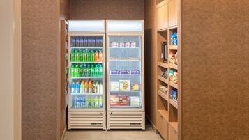 A narrow hallway with two refrigerated beverage dispensers stocked with various drinks and snacks.
