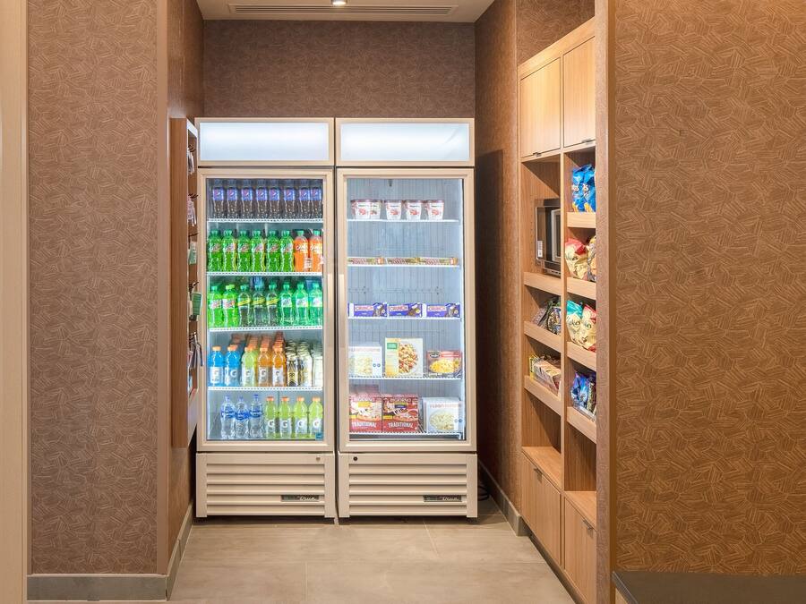 A narrow hallway with two refrigerated beverage dispensers stocked with various drinks and snacks.