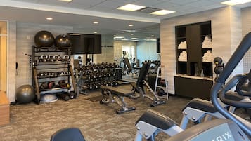 Une salle de sport équipée de divers appareils d’exercice, notamment des tapis de course, des appareils de musculation et des poids libres.