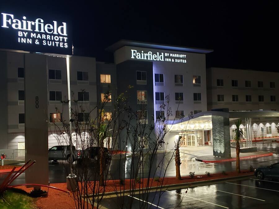 Un hotel Marriott Fairfield Inn & Suites de noche, con una entrada bien iluminada y un estacionamiento.