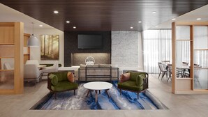 A modern lounge area with a round table, two green armchairs, a sofa, and a TV mounted on the wall.