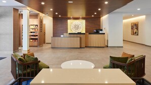 A modern lobby with a reception desk, seating area, and a vending machine.