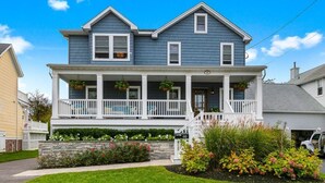 A two-story house with a front porch, a stone foundation, and a well-maintained garden.