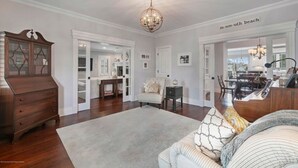 A spacious living room with a large wooden dresser, a chandelier, and a view of the dining area.