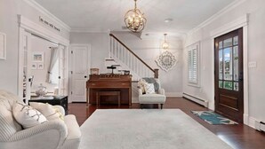 A spacious living room with a grand staircase, a piano, and a cozy seating area.