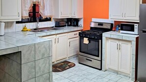 A kitchen with white cabinets, a stove, a microwave, and a sink. - Cozy 2 Bedroom Apt near Airport, Malls, Golfing, Mountains  (Arouca)