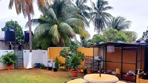 A courtyard with a seating area, potted plants, and a fenced enclosure with a birdcage. - Cozy 2 Bedroom Apt near Airport, Malls, Golfing, Mountains  (Arouca)