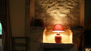 A stone fireplace with a red lamp, a wooden ladder, and a chair.