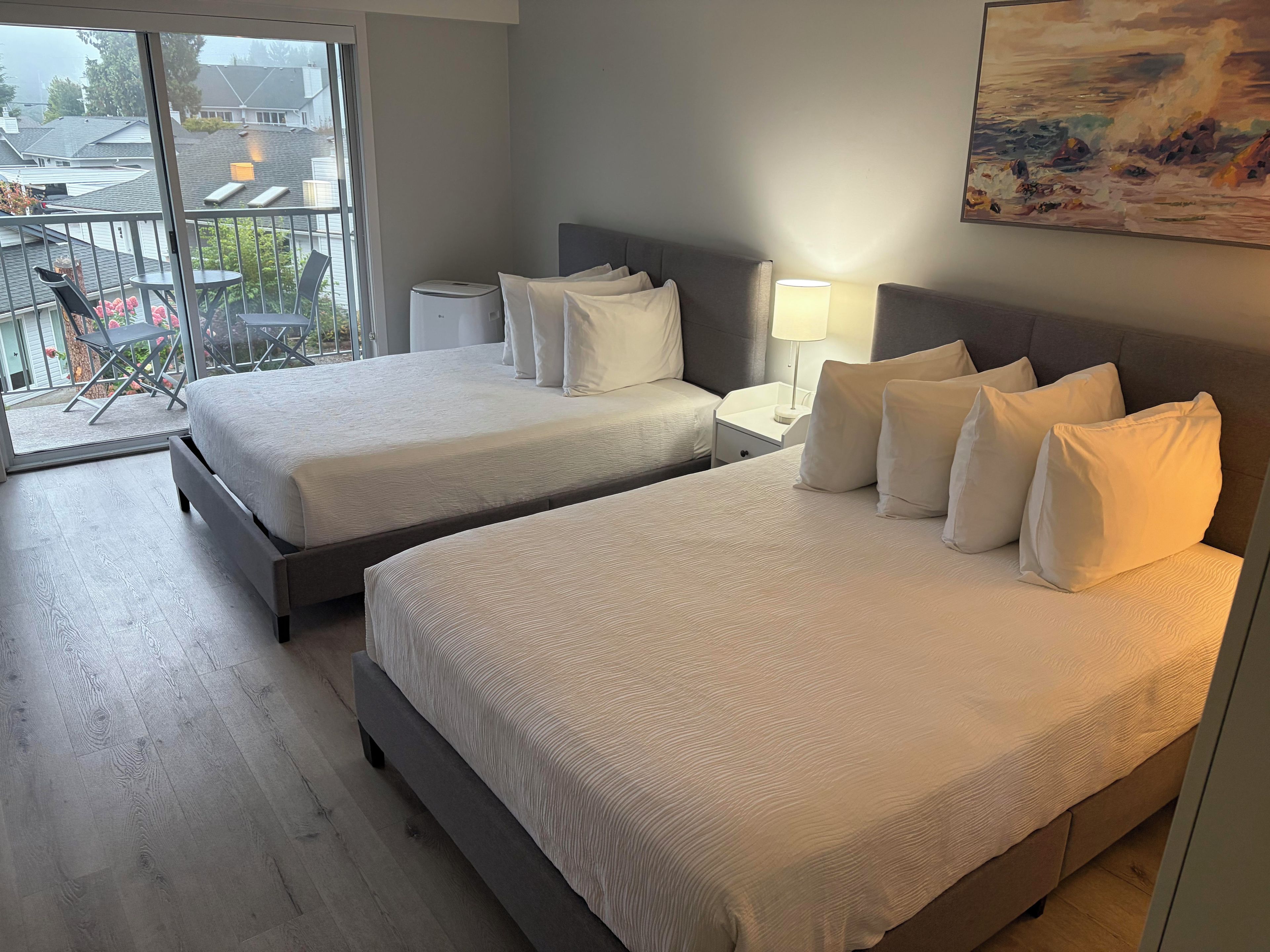 Habitación de hotel con dos camas, un balcón y un cuadro.