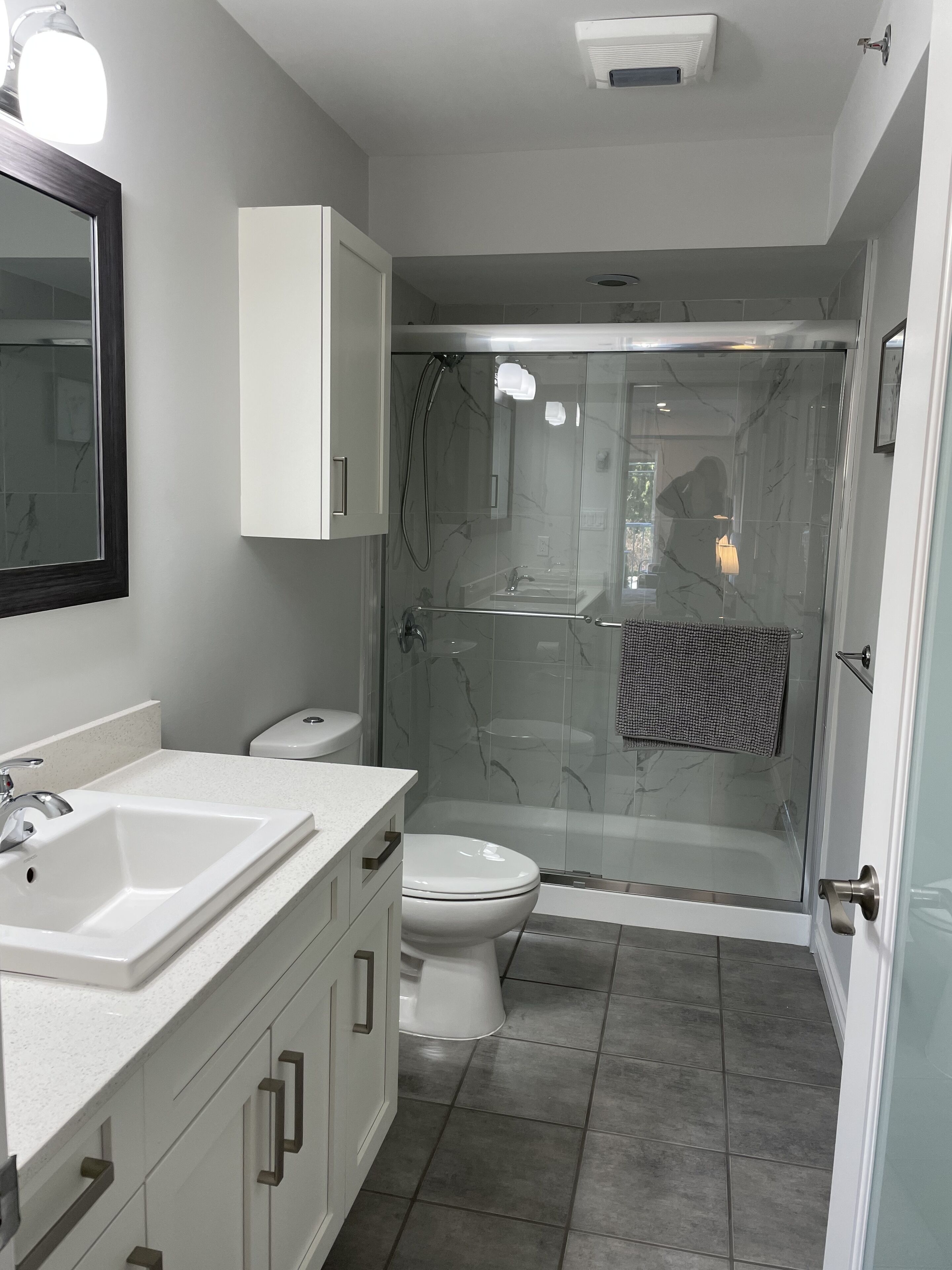 Un baño moderno con ducha acristalada, lavabo blanco y un inodoro.