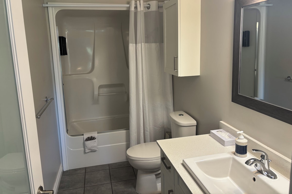 A bathroom with a bathtub, toilet, sink, and a mirror.