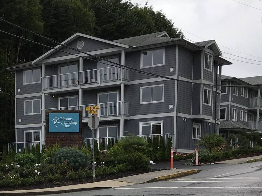 A multi-story hotel with balconies, a sign for 'Gibsons Landing Inn', and a 'DOUGALL' street sign.