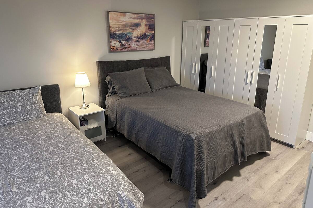A bedroom with a bed, a bedside table with a lamp, a wardrobe, and a painting on the wall.