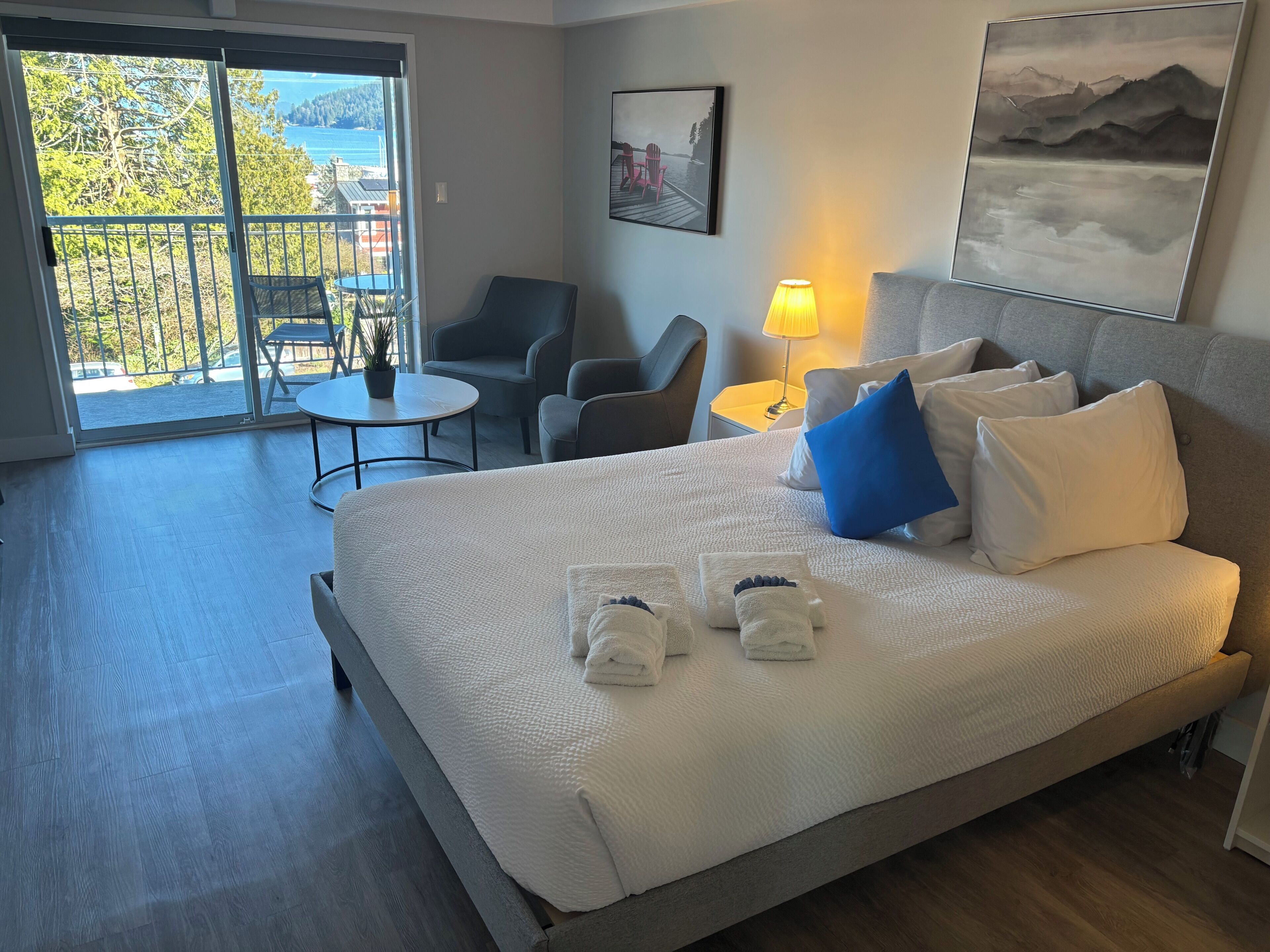 Une chambre d’hôtel avec un lit, un bureau, une chaise, une table et un balcon avec vue.