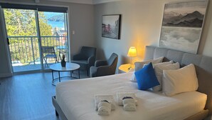 Habitación de hotel con cama, escritorio, silla, mesa y balcón con vistas.