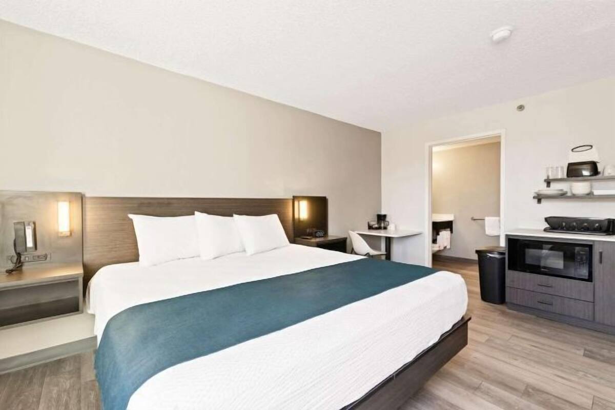 Une chambre d’hôtel équipée d’un lit, d’une table de chevet, d’une lampe et d’un coin cuisine.