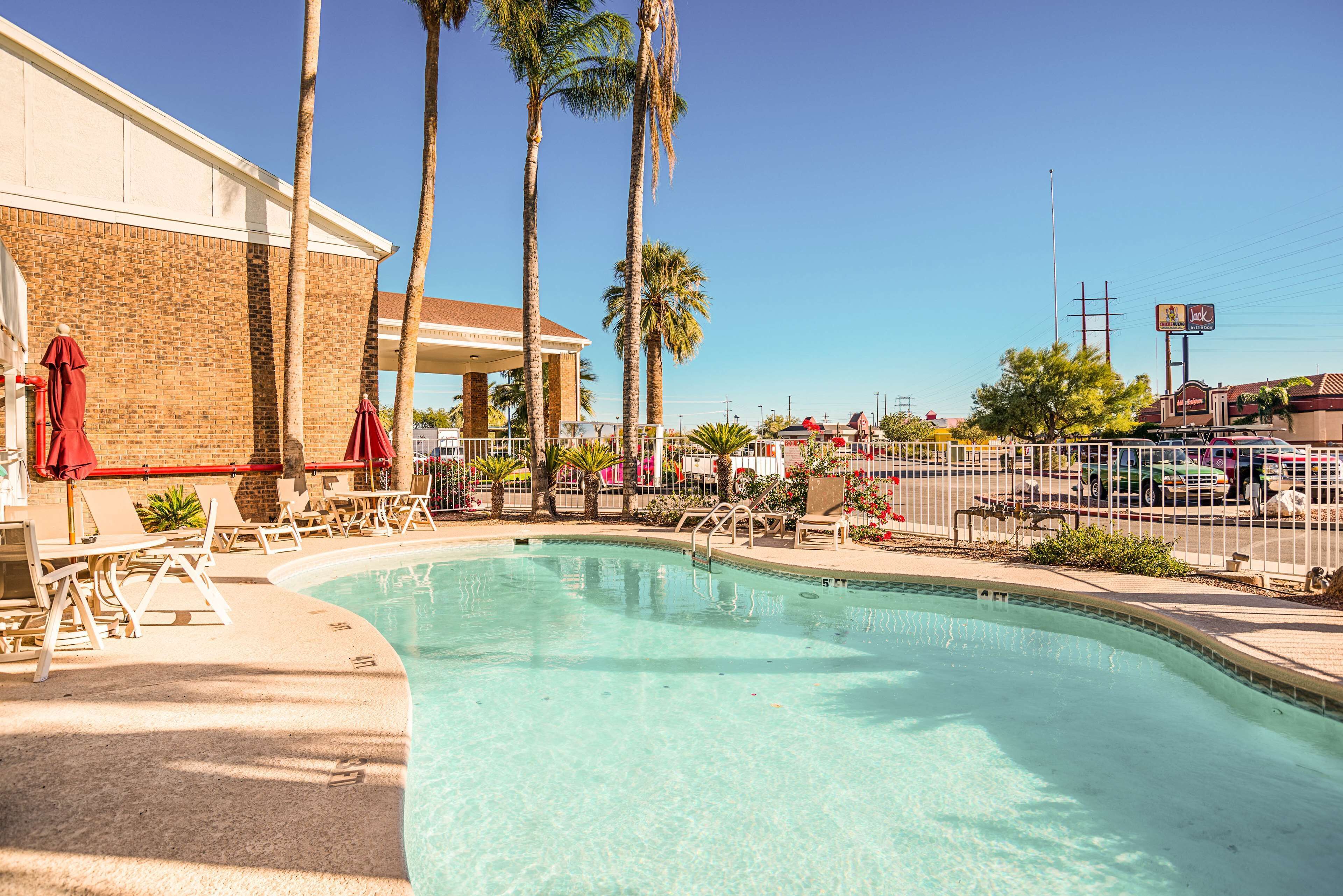 A pool area with lounge chairs and a brick building.