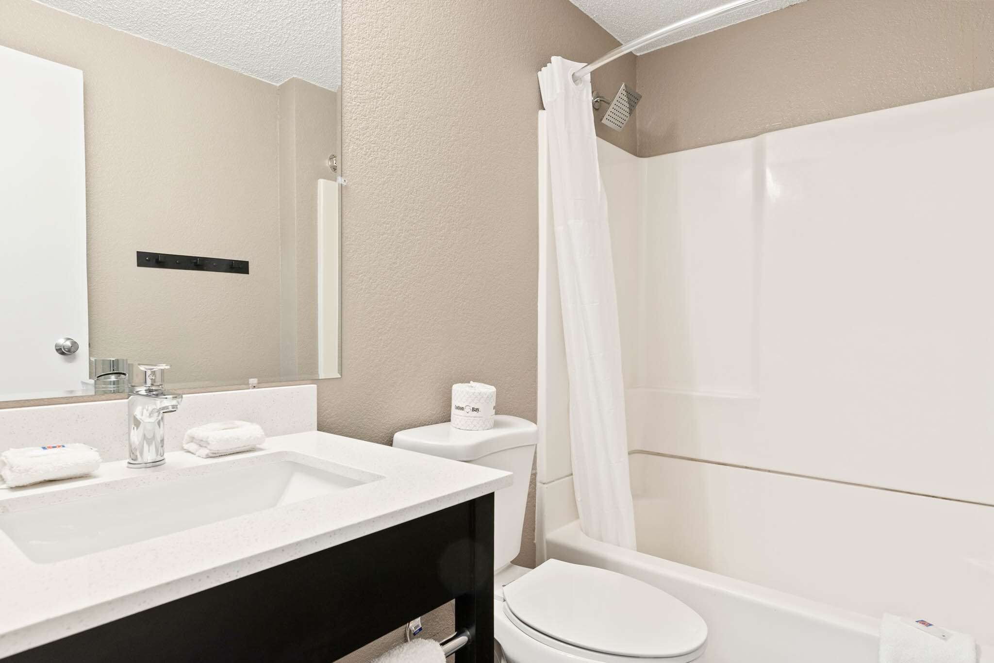Une salle de bain moderne équipée d’un lavabo, d’un miroir, de toilettes et d’une douche.