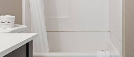 Un baño moderno con inodoro blanco, bañera y cortina de ducha.