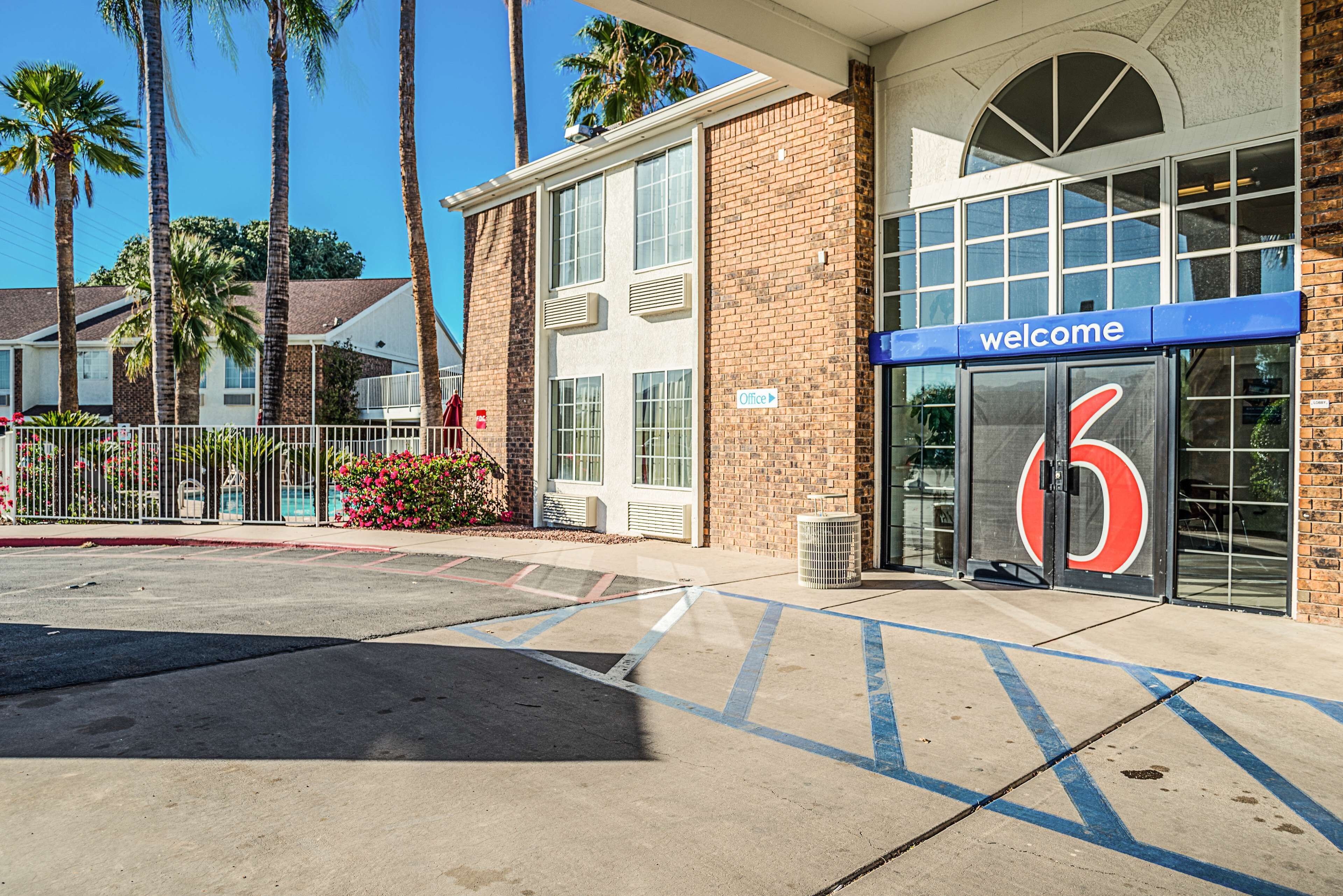 A hotel entrance with a 'welcome' sign, a large number '6' sign, and a brick building facade.