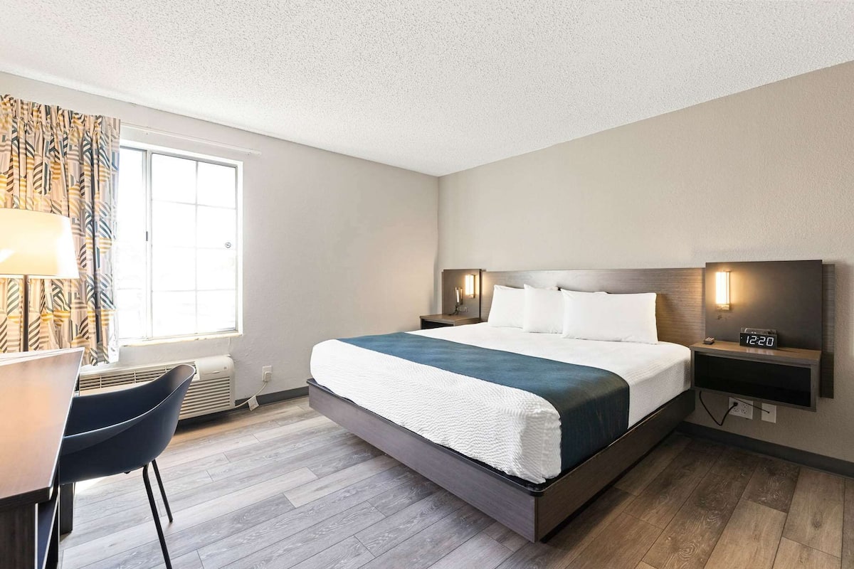 Une chambre d’hôtel avec un lit, des tables de chevet, un bureau et une chaise.