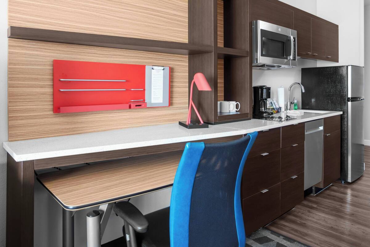 Una cocina moderna con microondas integrado, cafetera y refrigerador.