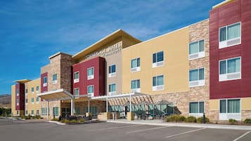 A hotel with a modern design, featuring a mix of red and beige colors, and a clear sky.